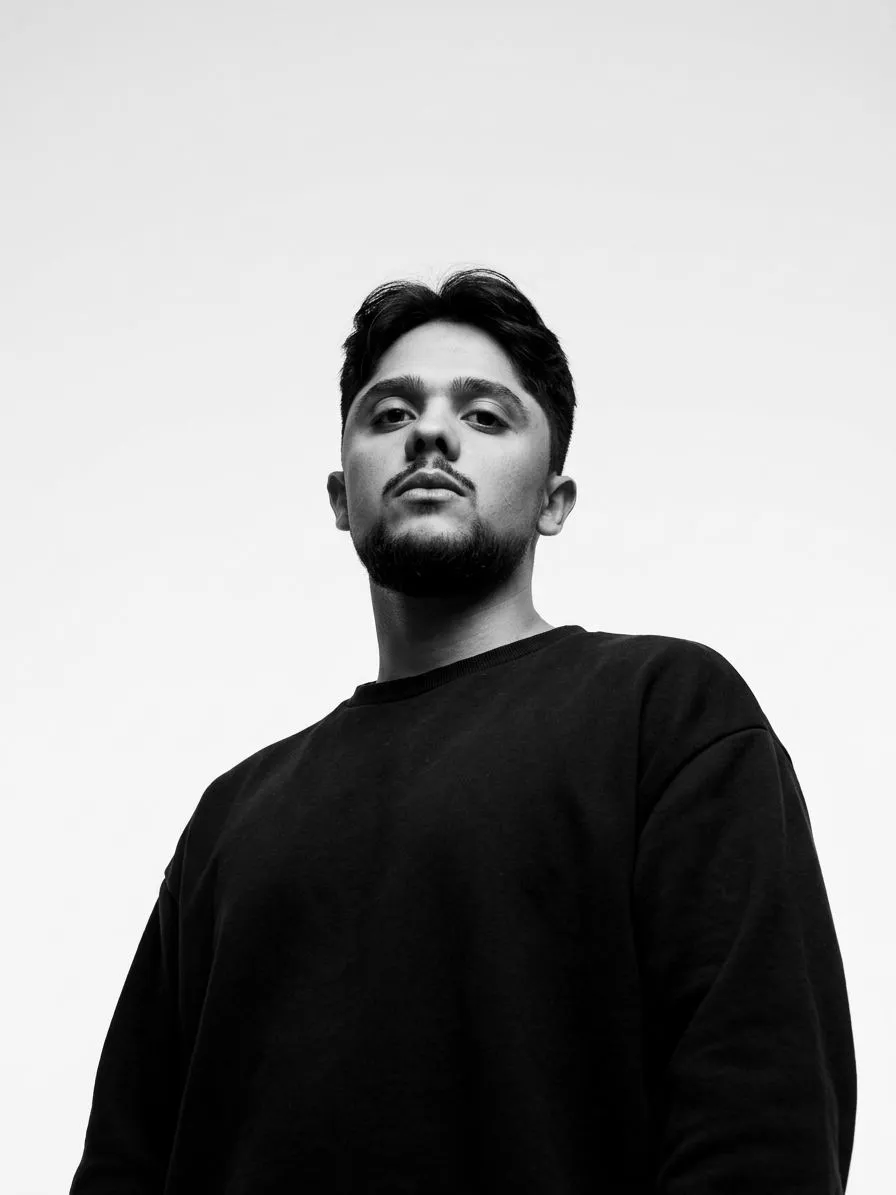 Retrato em preto e branco de Bruno Santos, fotografado de baixo para cima contra um céu branco.